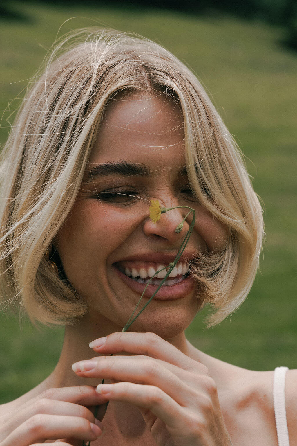 Portrait of a woman with short blond hair in a natural setting.