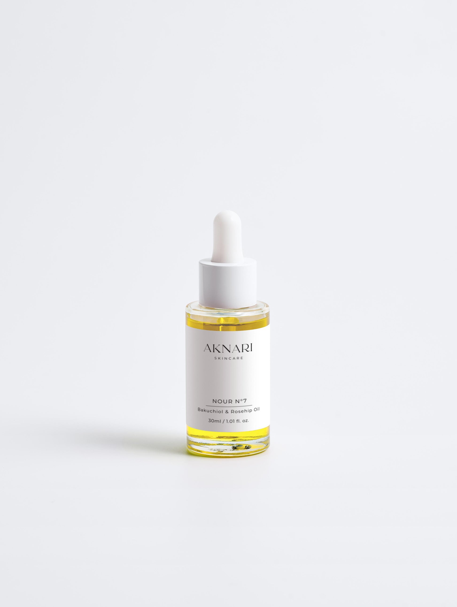 Glass dropper bottle with white label and oil inside in front of white background